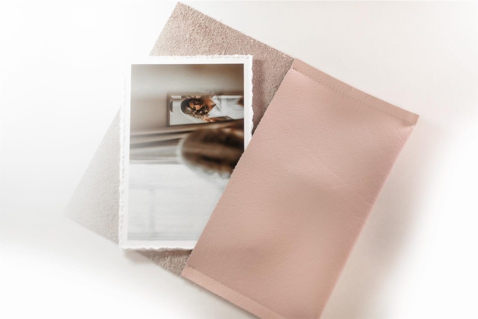 A pink leather wallet holding a collection of deckle edged archival quality fine art prints