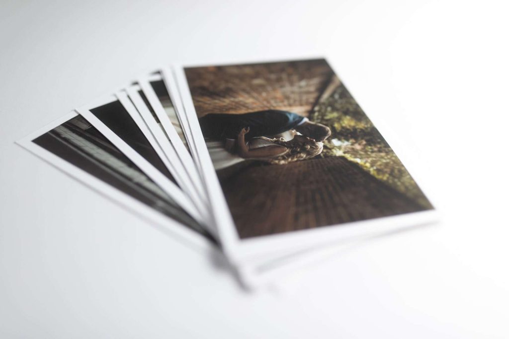 A pile of fine art prints with the top photo showing a bride and groom kissing