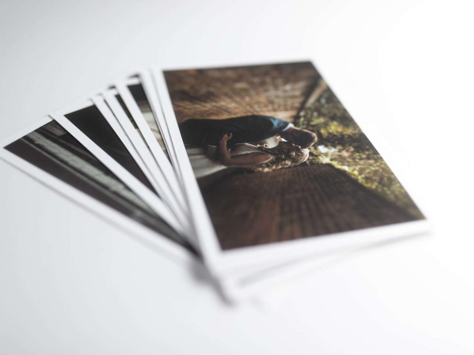 A pile of fine art prints with the top photo showing a bride and groom kissing