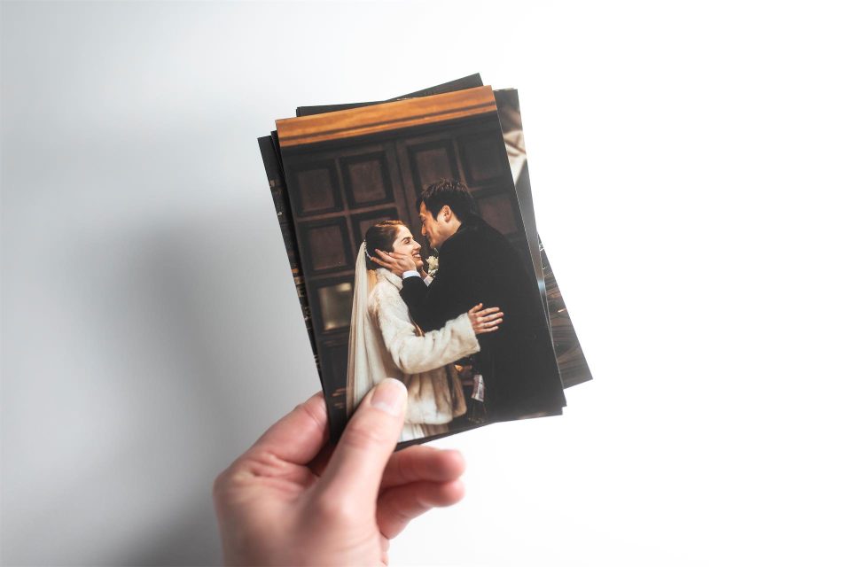 A hand holding several fine art prints of a wedding