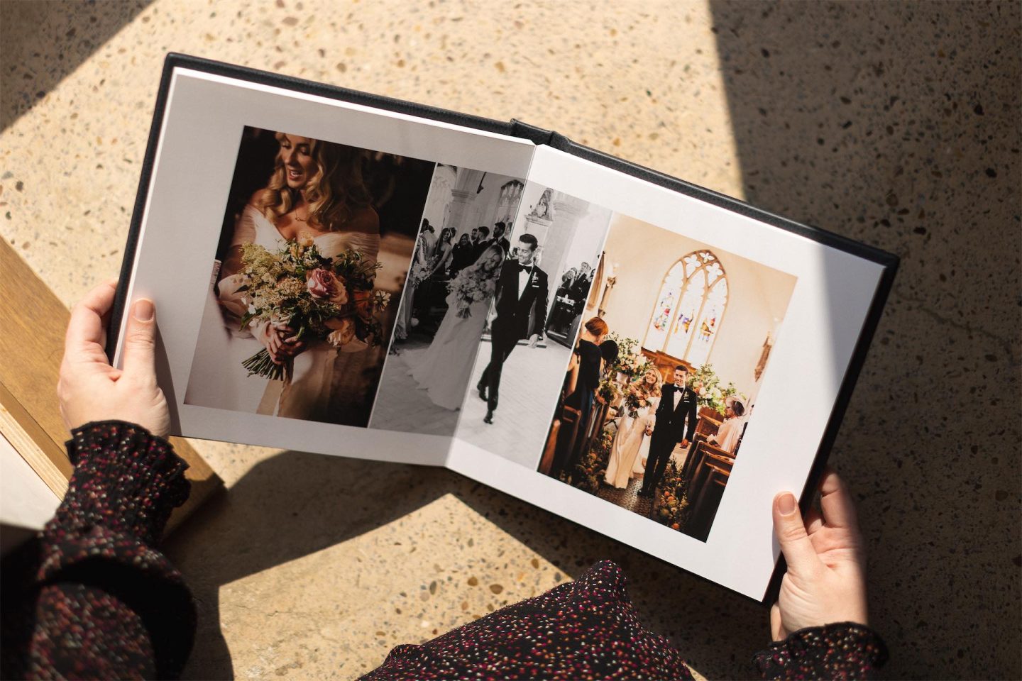 A professional photo book open on a woman's lap