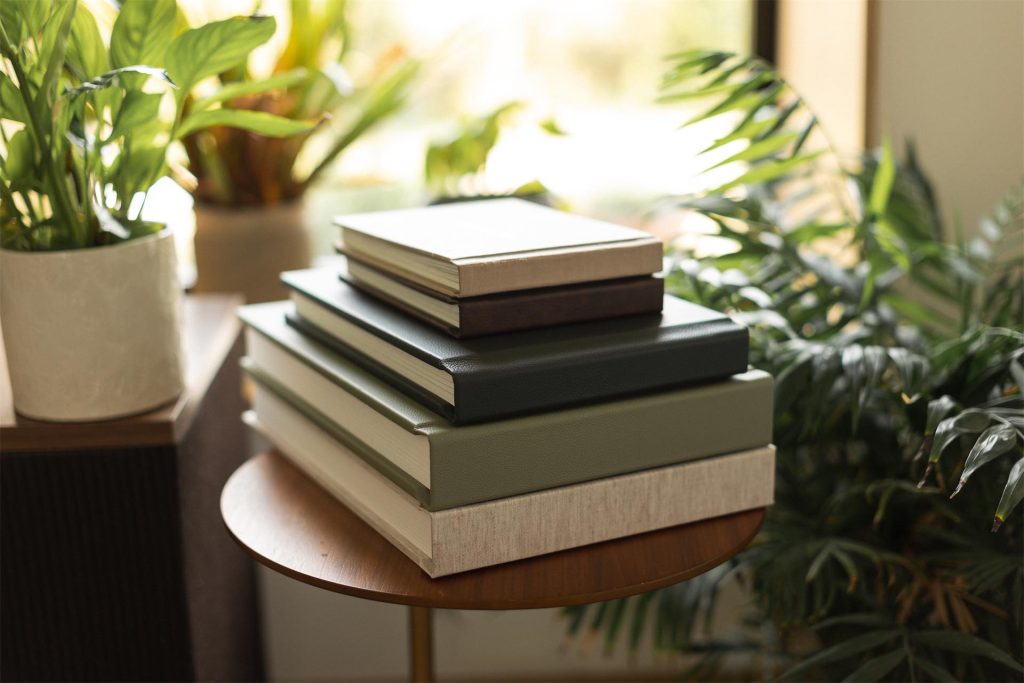 A collection of photo books stacked and with a window behind