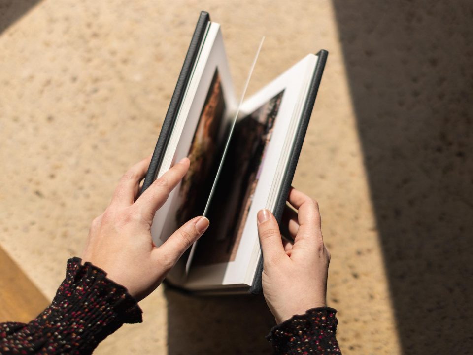 woman opening fine art printing album book on a table