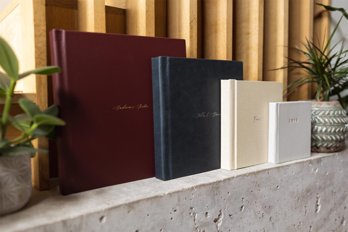 a row of photo albums on a shelve next to plants 