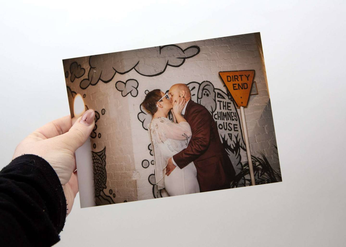 a bride and groom kissing during their evening reception with a graffiti wall behind them