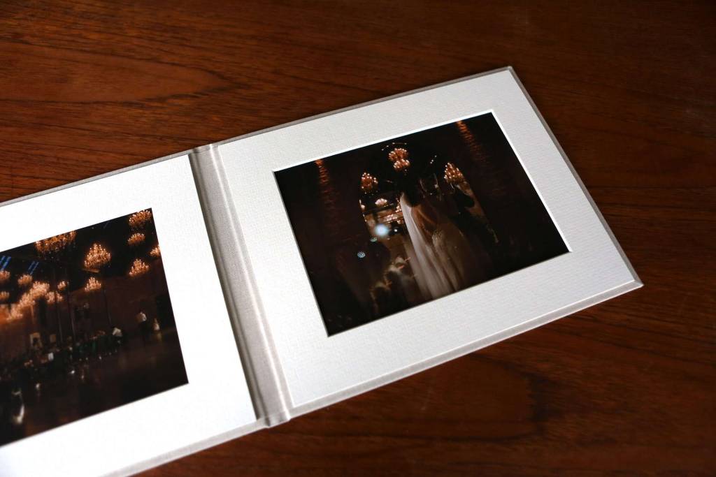 A presentation folio with fine art prints open on a table. The photos inside the folio are from a wedding.