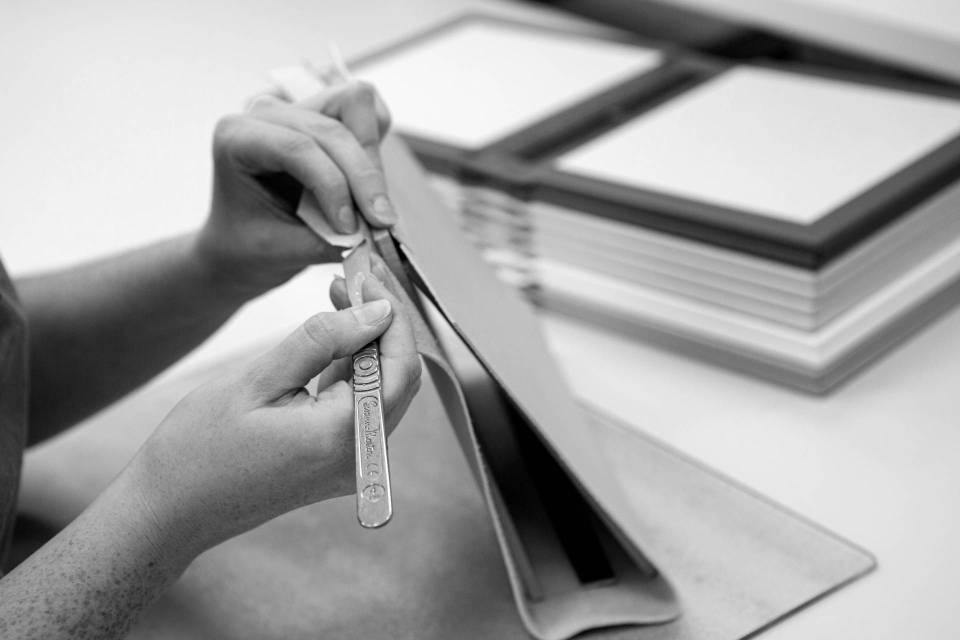 A photo of a book binder's hands in Folio's Yorkshire, UK workshop making a leather-bound photo album cover