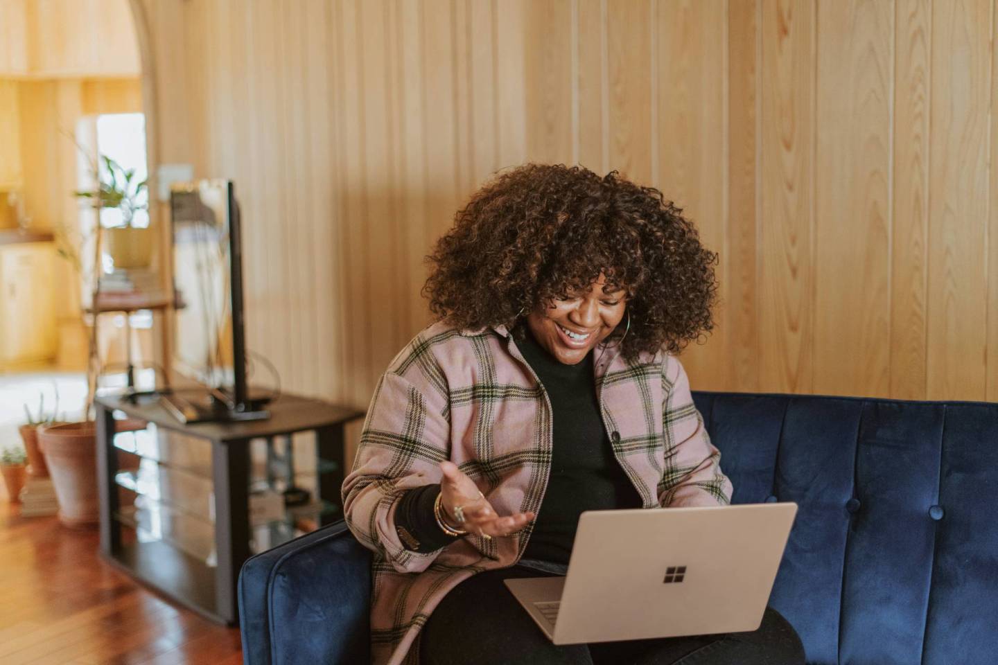 A lady siting on a sofa with a laptop on her lap and having a Zoom call