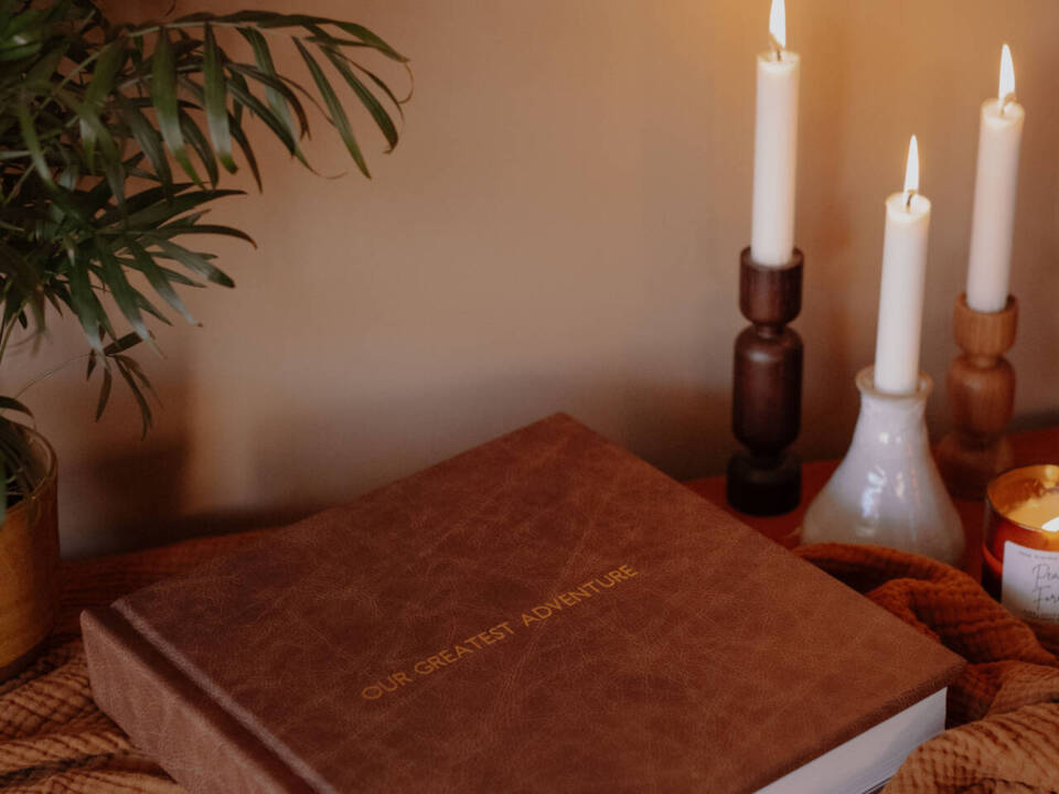 a dark brown album in on a blanket with candles and a plant