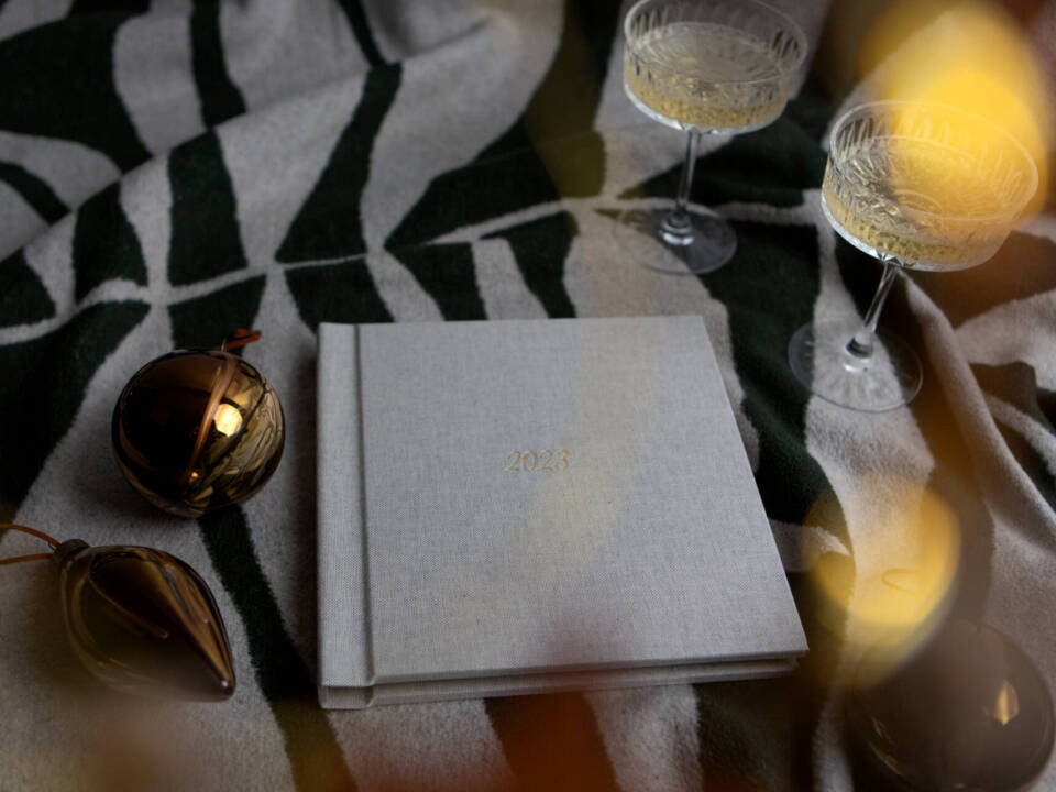 wedding album in christmas style setting with baubles and Prosecco in a glass