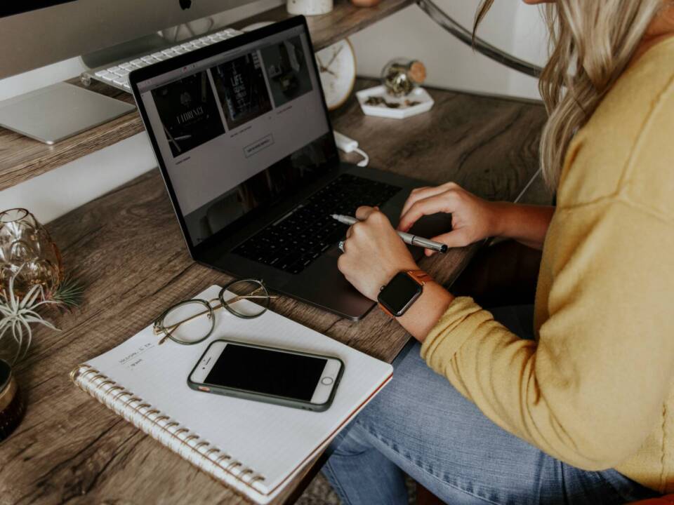 female photographer on laptop with to do list next to laptop