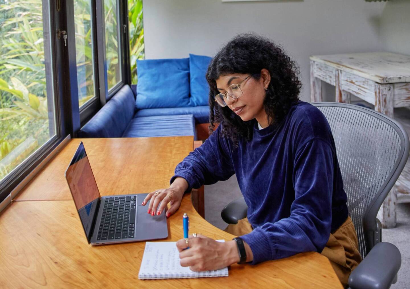 female photographer writing a to do list next to laptop on desk 