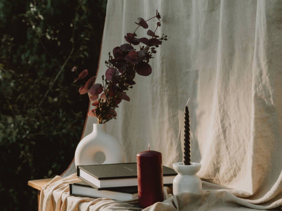 an album display in an autumn style with vase, candle and dark purple flowers