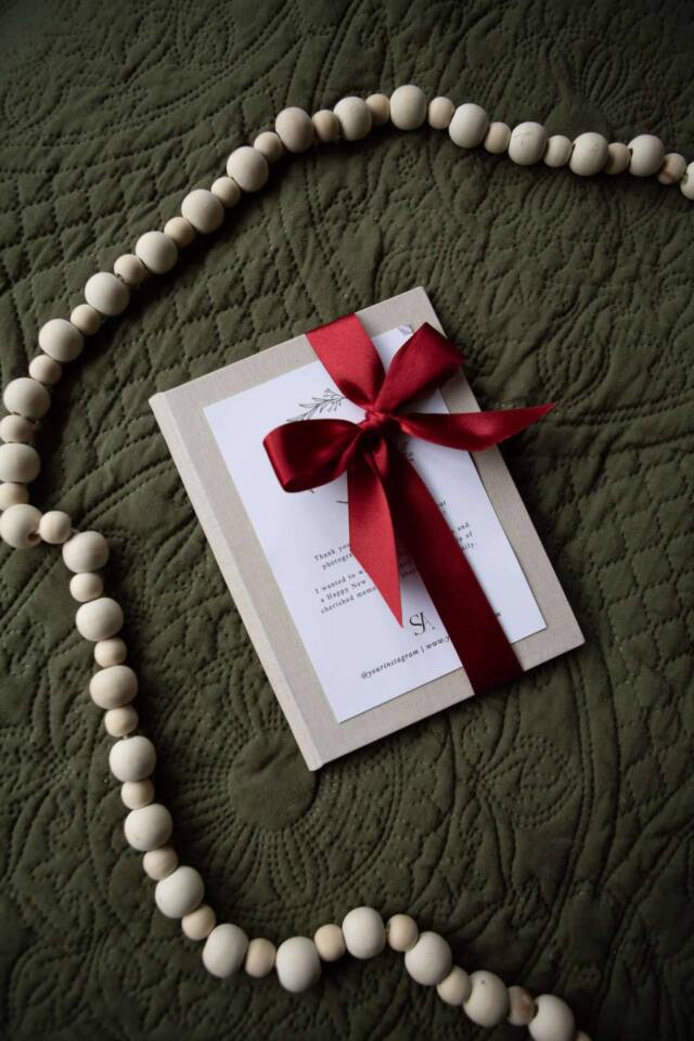 Christmas Thank You Folio on a rug and tied in a red ribbon