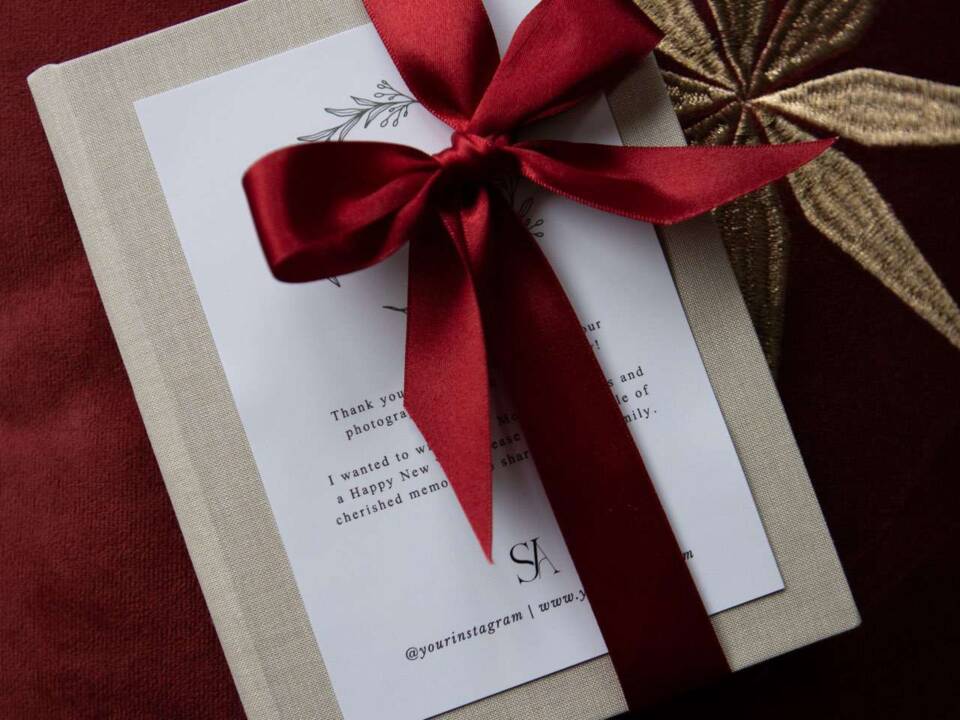 Thank you folios tied up with a red ribbon on a red cushion with gold star decoration