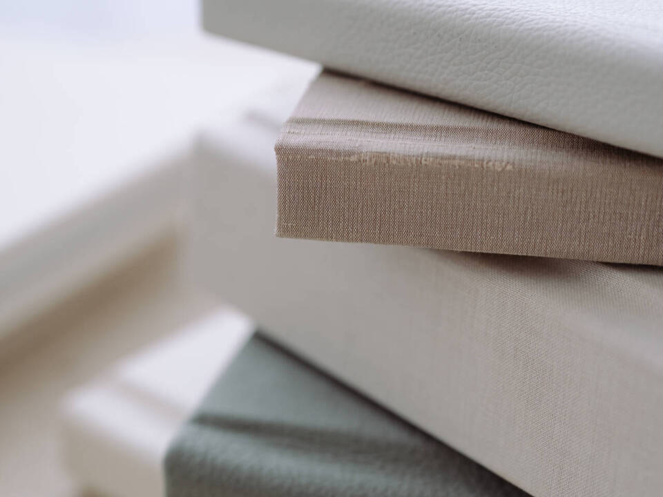 a stack of neutral coloured photo albums on a coffee table