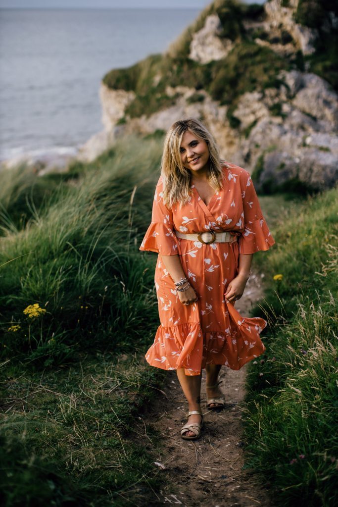 a female on a beach cliff in summer clothing walking up a hill 