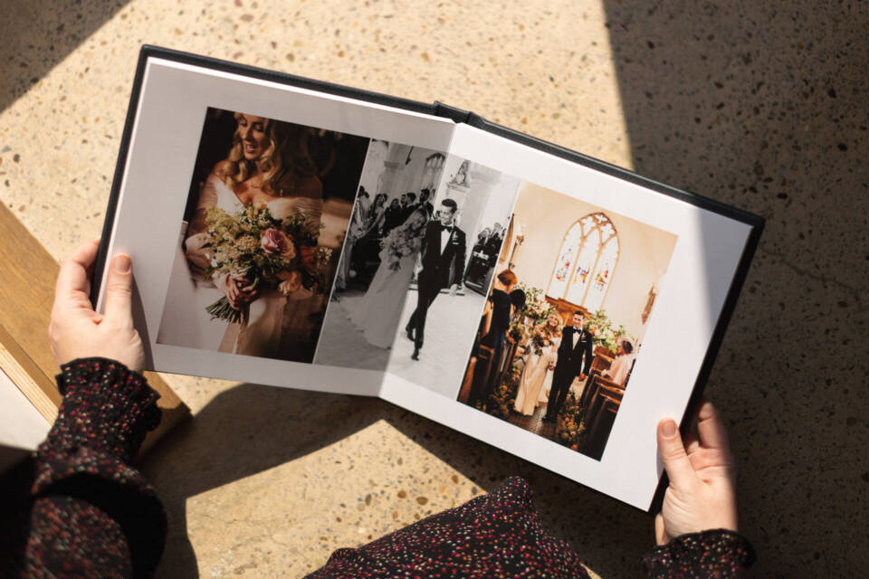 woman holding a fine art album open with wedding images 