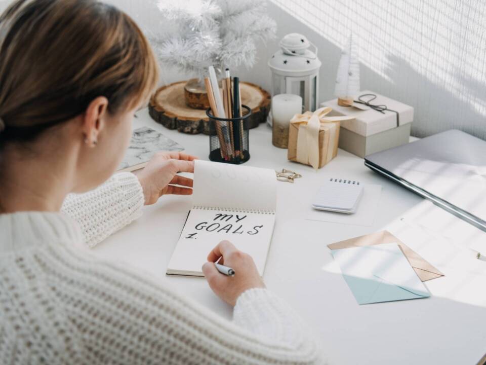 woman writing her goals on a note pad on her desk