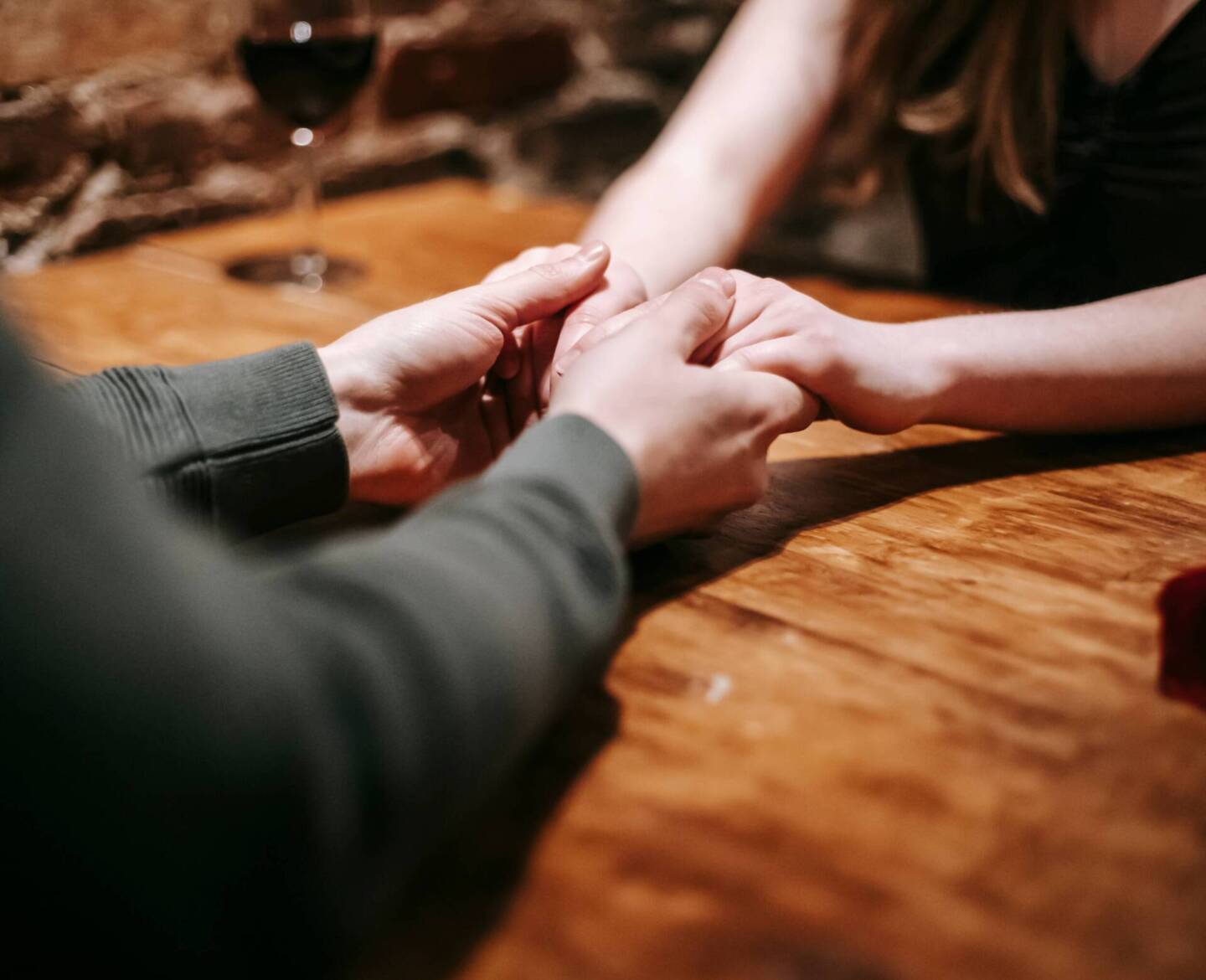 couple holding hands over wooden table on Valentine's Day date 