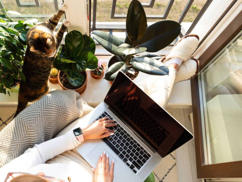 woman working on laptop next to balcony