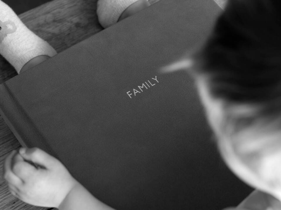 black and white image a child holding a family album with a nostalgia feeling