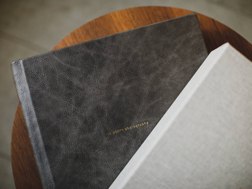 two leather photo albums on a round wooden table