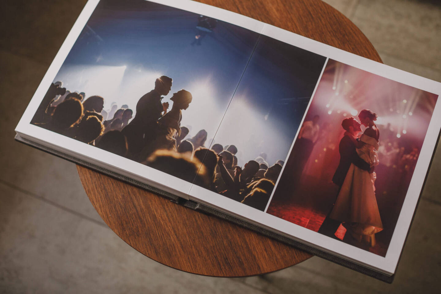 open wedding album on round wooden table with first dance images 