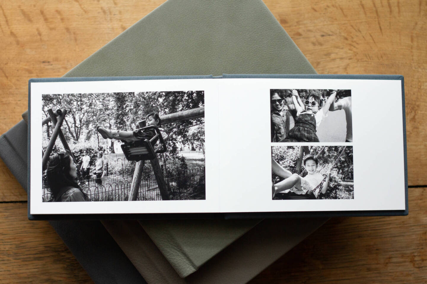 an open luxury wedding album on a stack of other wedding albums on a wooden floor 