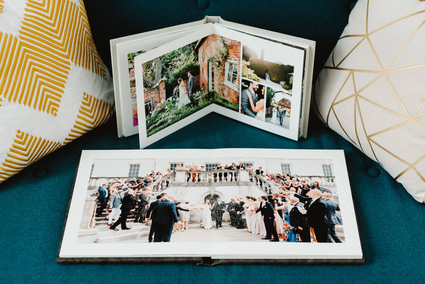 two open wedding albums on a sofa displaying wedding photos 