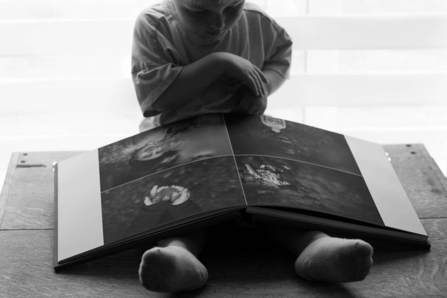 child sat on floor looking at open photo album 