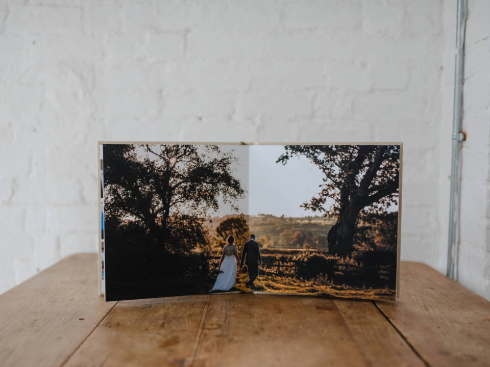 an open wedding album stood up on a wooden table