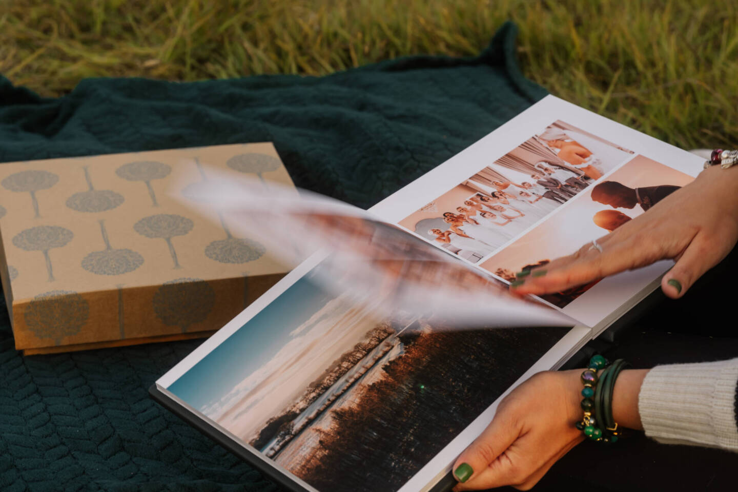 a woman flipping through a fine art album in a field on a blanket 