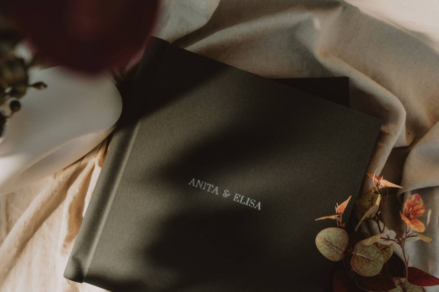 a leather fine art album on a nude blanket with plants