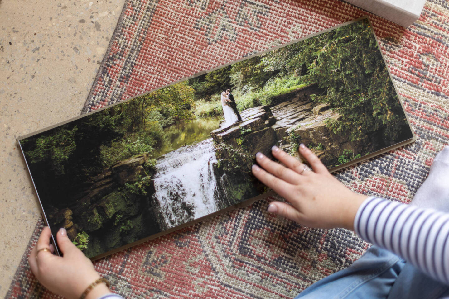 close up image of a woman in a striped t shirt flipping through a photo album on a red rug