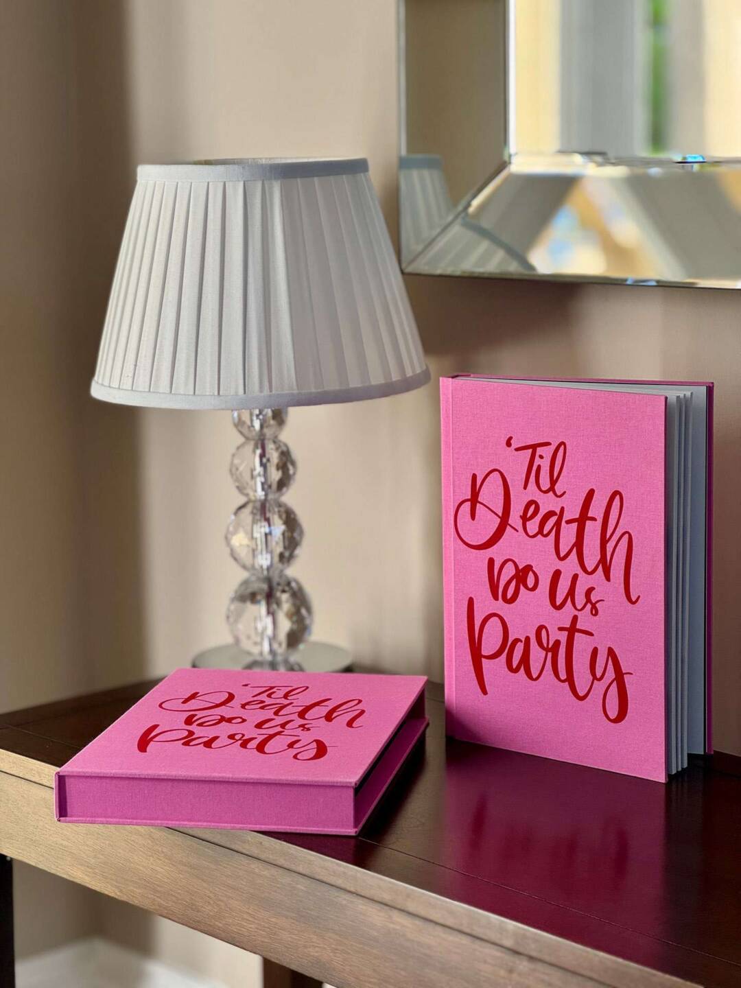A rhubarb pink coloured fabric wrapped photo album and slip case in a coffee table book style on a sideboard
