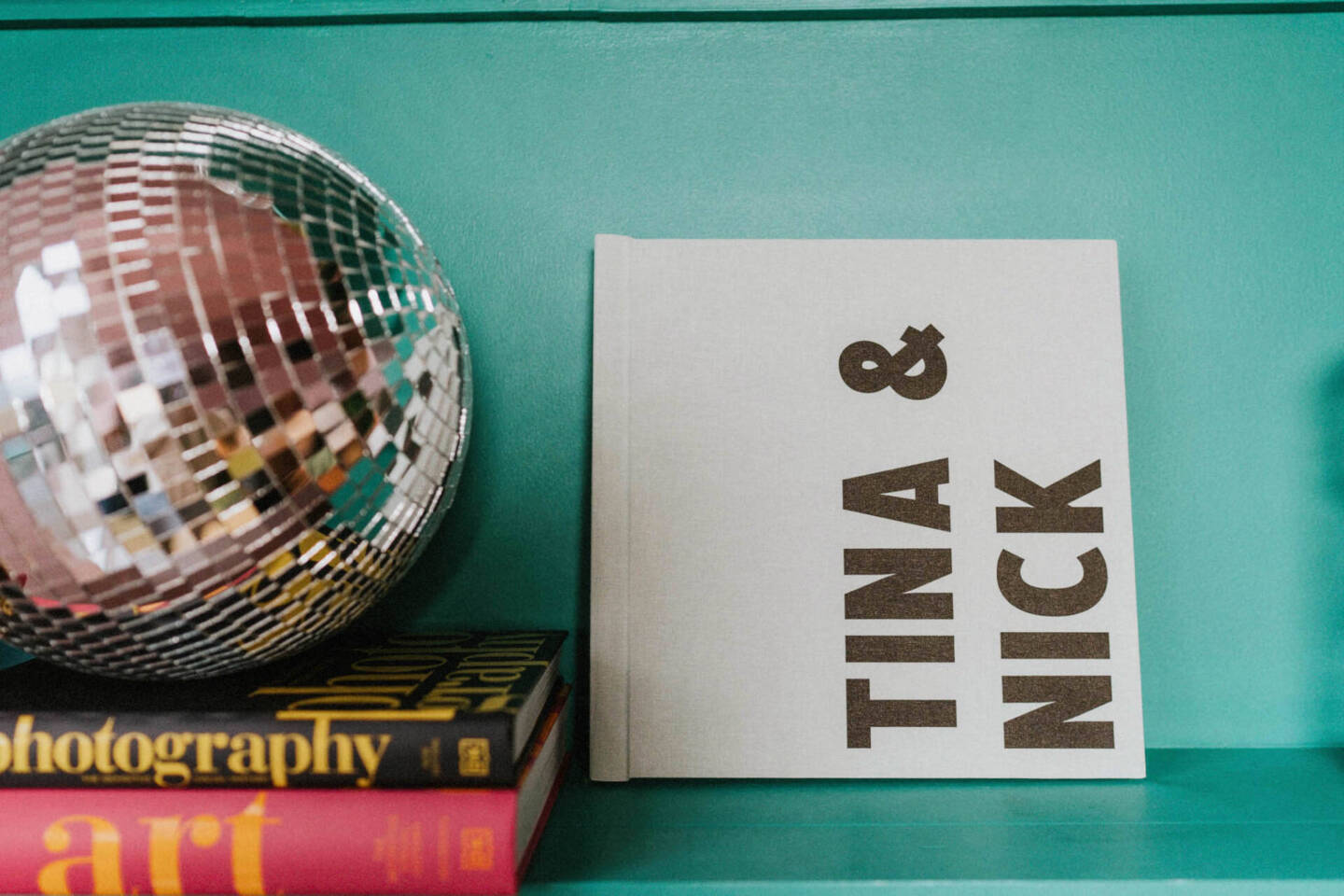 bespoke photo album personalisation which reads "Tina & Nick" in black ink vertically on a pale green fabric album.