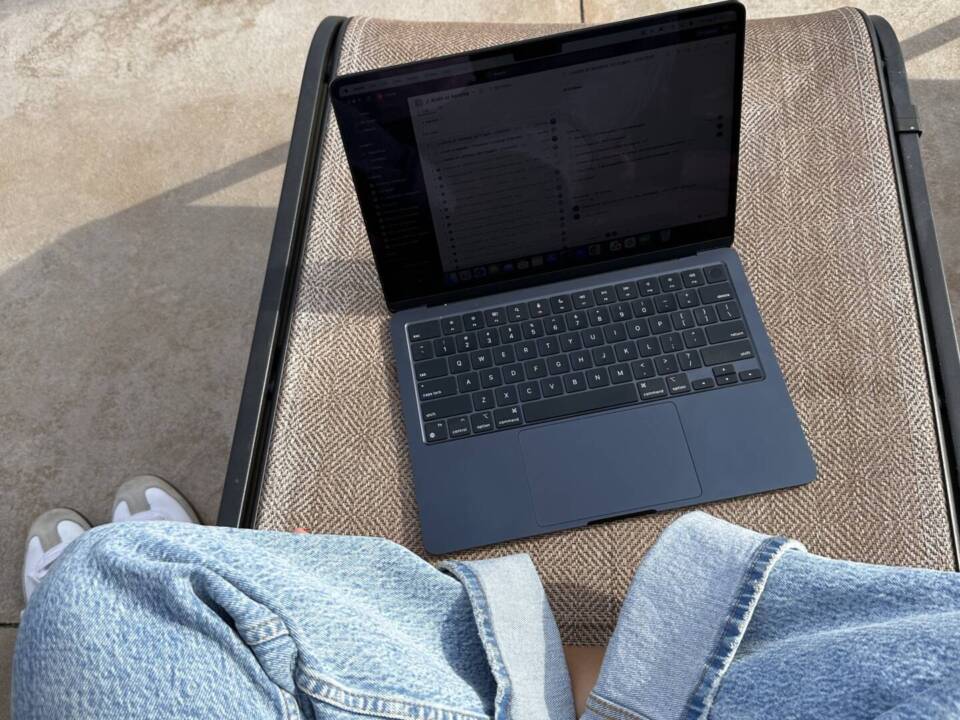 a photographer working on her laptop working with photography clients. She is wearing jeans and is crosslegged.