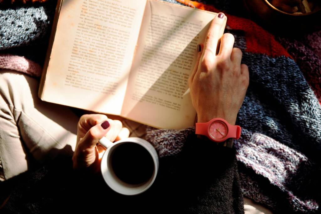a wedding photographer reading a book and drinking coffee to help survive wedding season