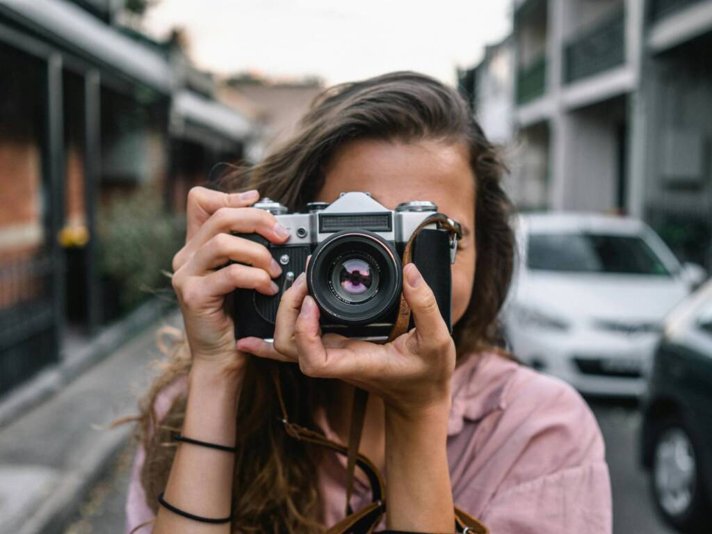 a female wedding photographer in a pink top holding a film camera